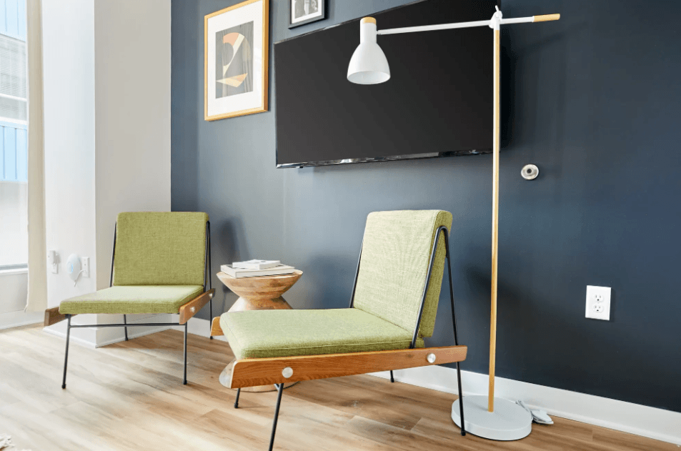 a living room with two chairs and a lamp and a television