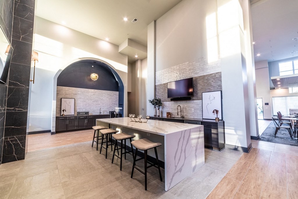 a large kitchen with a marble counter top and bar stools