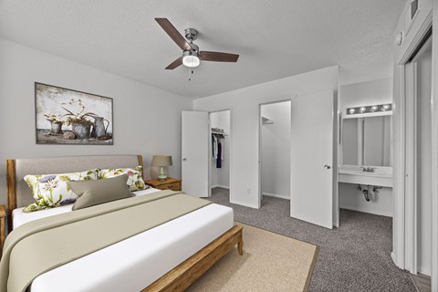 A bedroom with a bed, a ceiling fan, and a painting on the wall.