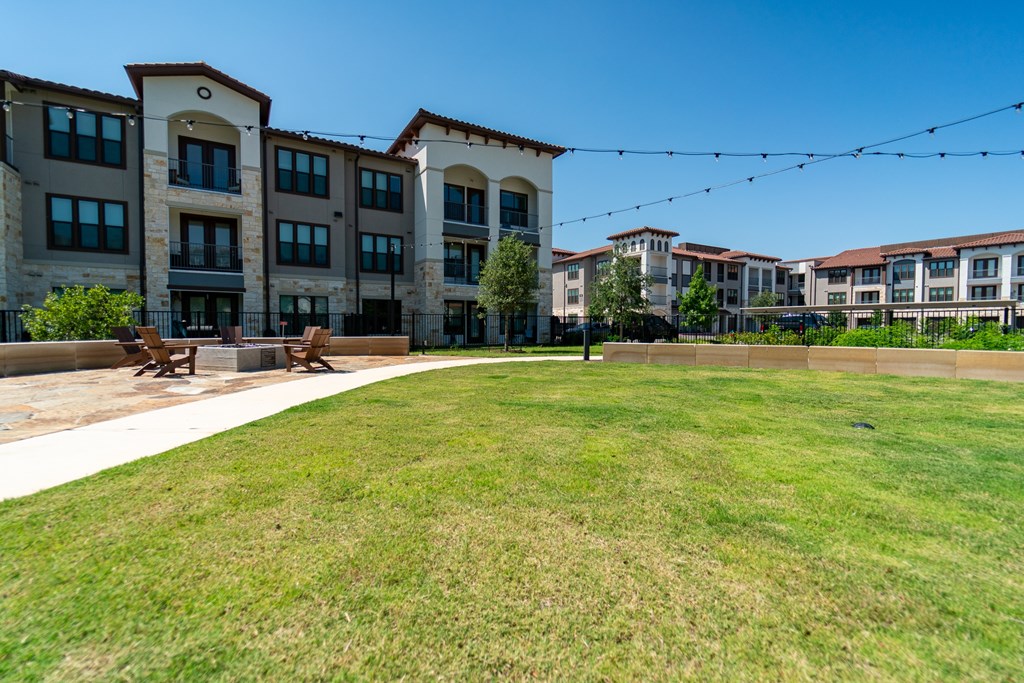 A grassy area in front of a building with string lights above.