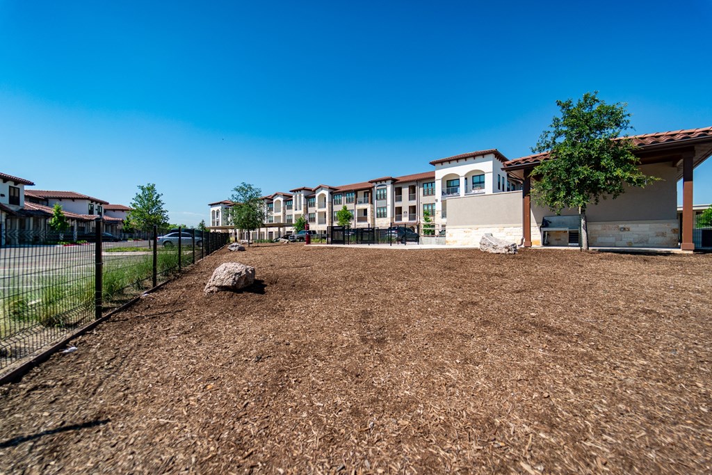 A large open field with a fence and a building in the background.