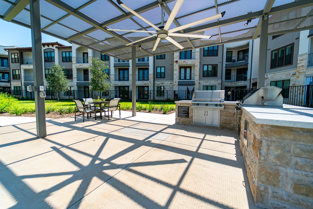 A patio with a white umbrella and a table with chairs underneath it.