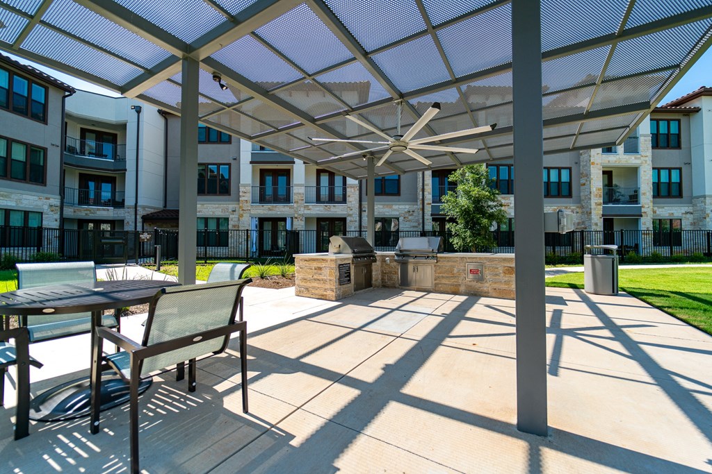 A patio with a table and chairs is covered by a white canopy.