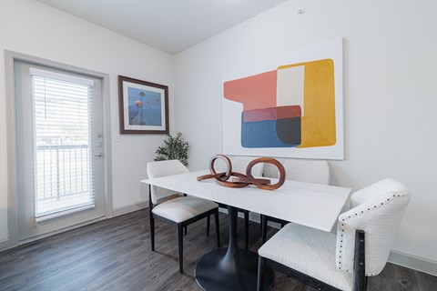 a dining room with a white table and chairs and a window