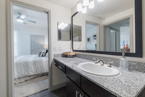 a bathroom with a sink and mirrors and a bedroom with a bed