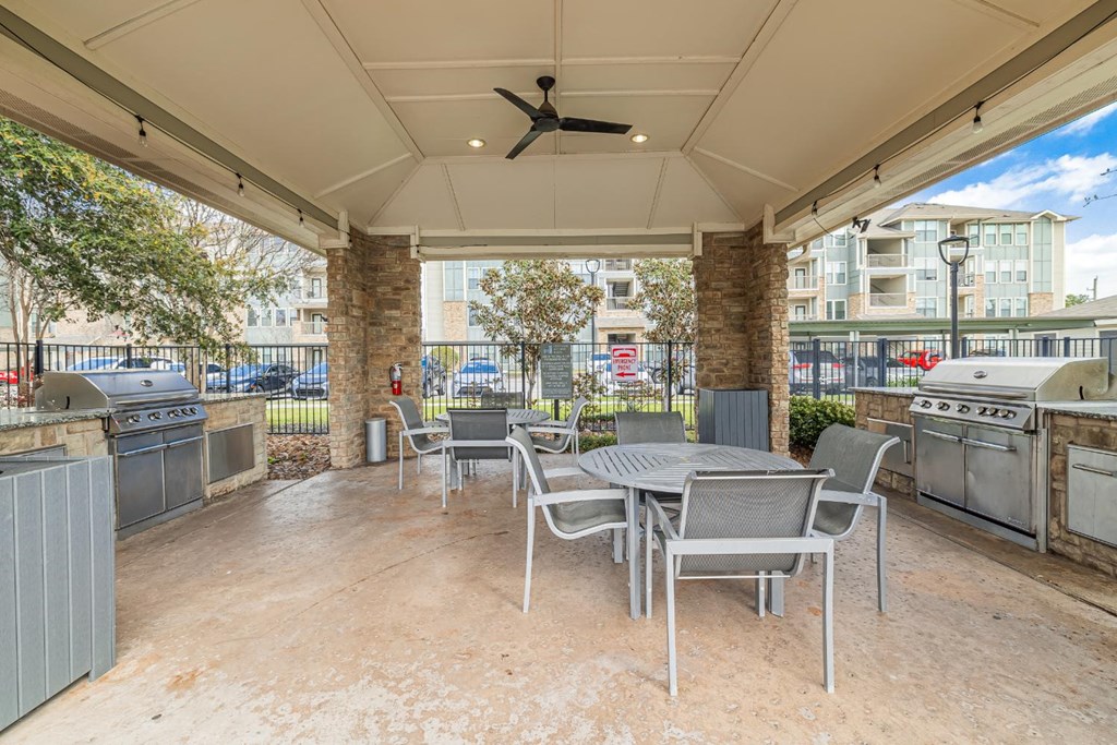 a patio with a table and chairs and a grill