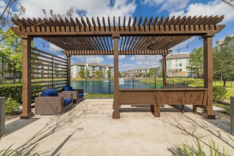 a patio with a pool and a wooden pergola
