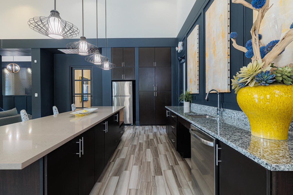a large kitchen with black cabinets and a yellow vase