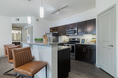 a kitchen with black and white appliances and a counter with chairs