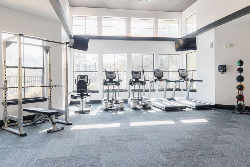 a gym with cardio equipment and windows in a building