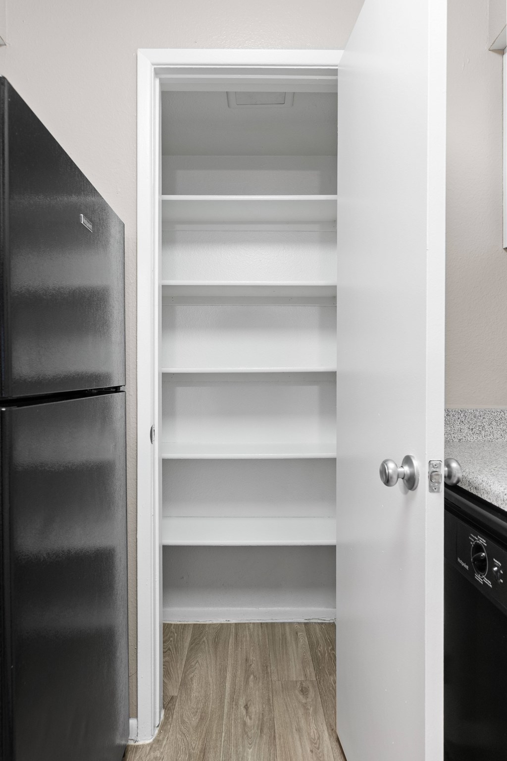 A black refrigerator is next to an open white door.