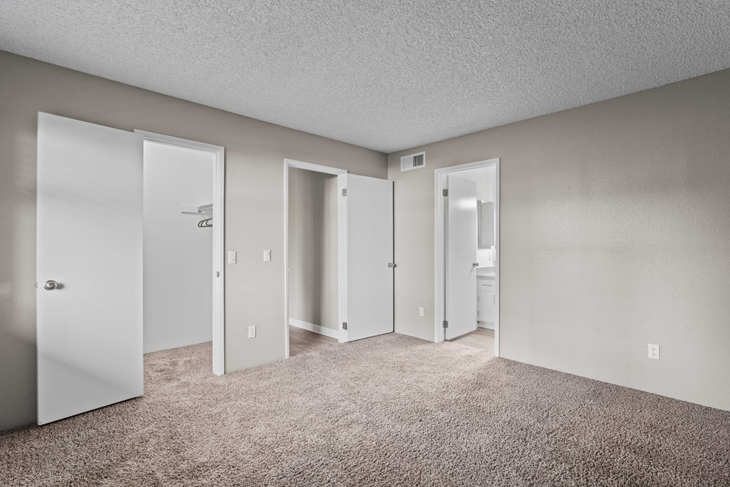 A room with four doors and carpeted floor.