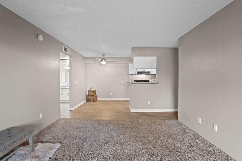A room with a ceiling fan and a rug on the floor.