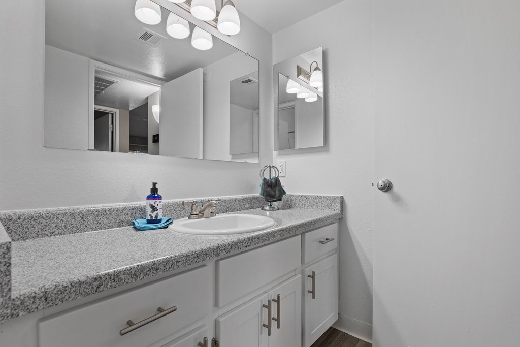 A bathroom with a sink, mirror, and cabinets.