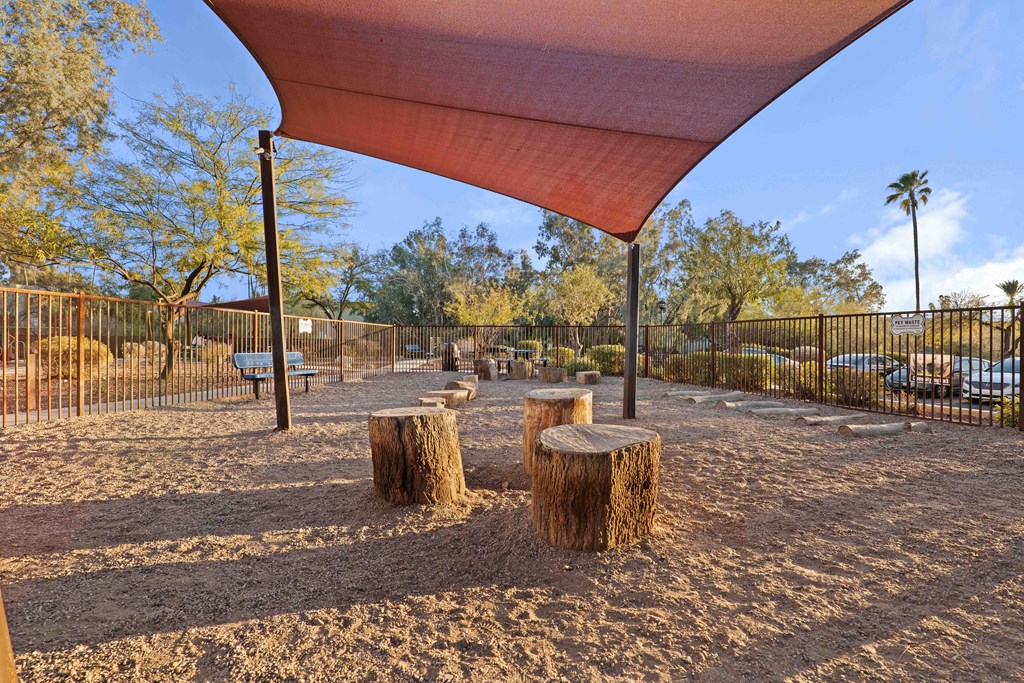 A playground with a red canopy and sandy ground.