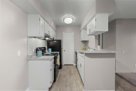 A kitchen with white cabinets and a black refrigerator.