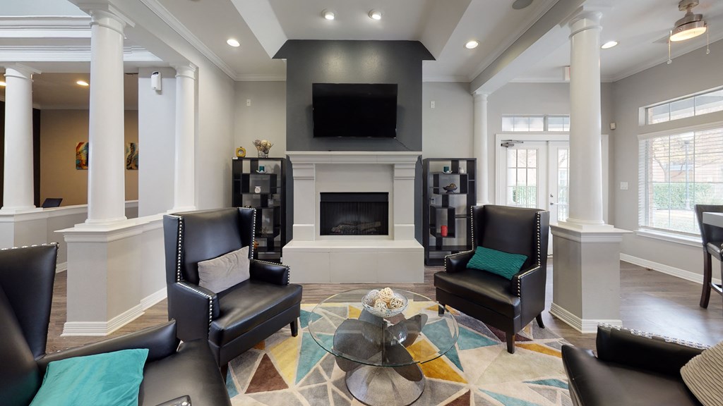 a living room with black leather chairs and a fireplace
