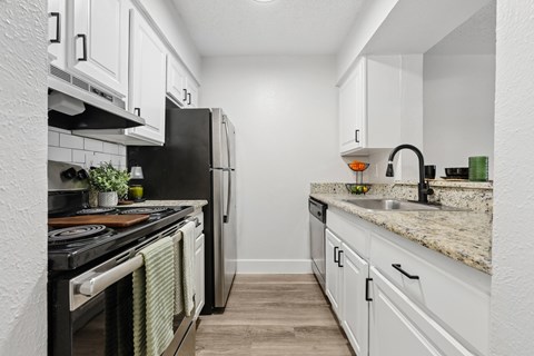 A kitchen with white cabinets and a black refrigerator.