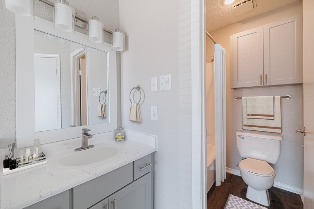 A white bathroom with a toilet, sink, and mirror.