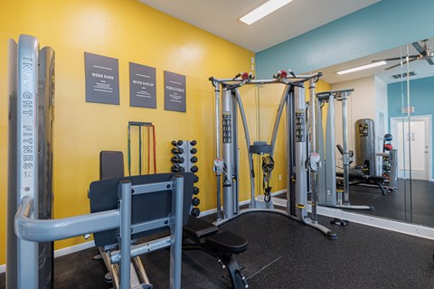 A gym with a yellow wall and a variety of equipment.