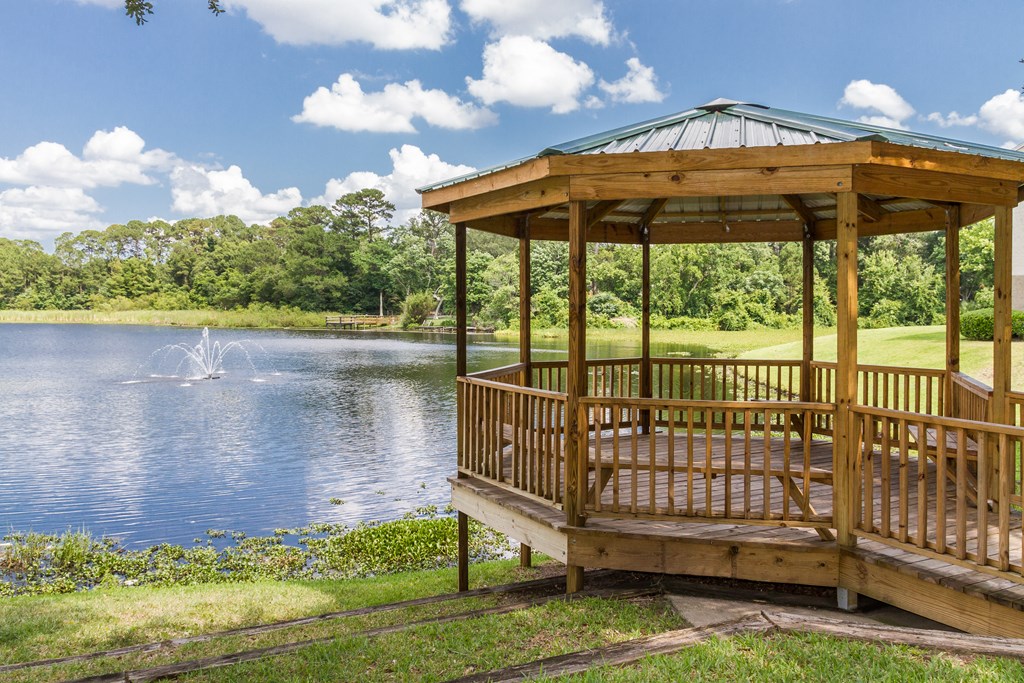 a gazebo by a pond with a fountain