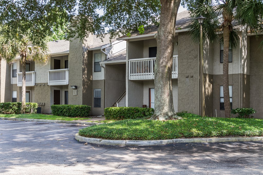 an apartment building with a street and trees in front of it