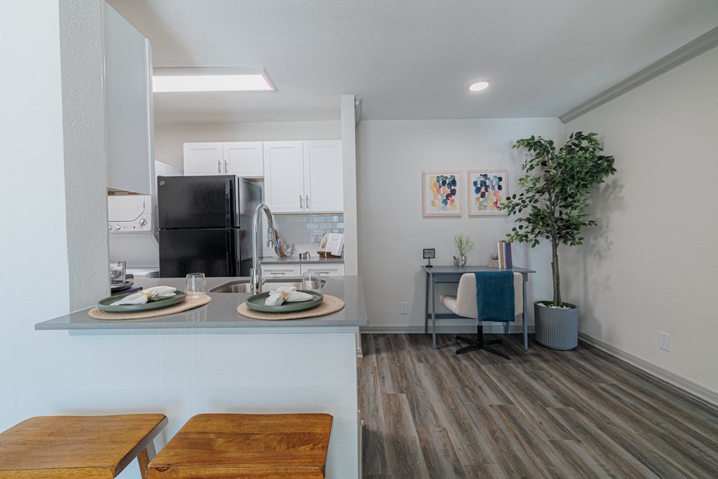 an open kitchen and living room with a dining table and a black refrigerator