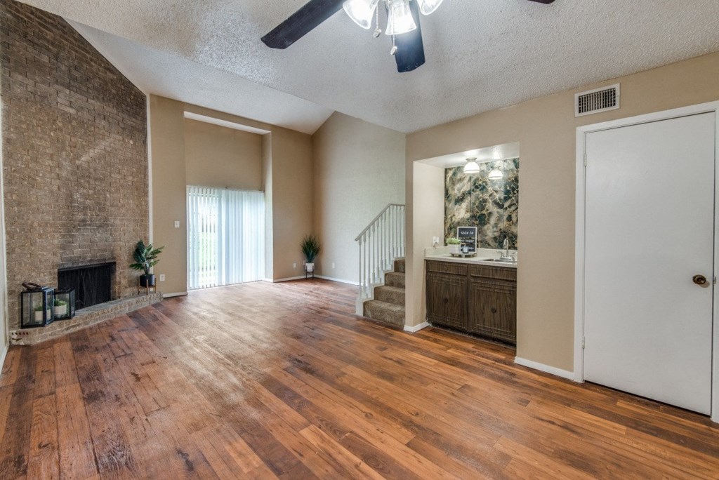 an empty living room with a fireplace and wooden floors