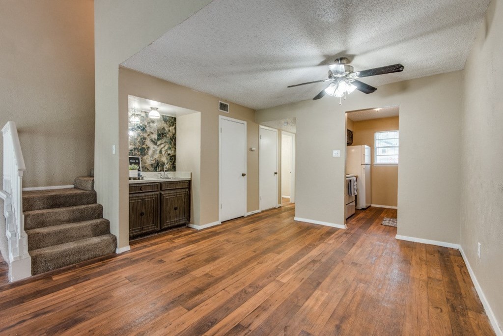 an empty living room and kitchen with a ceiling fan