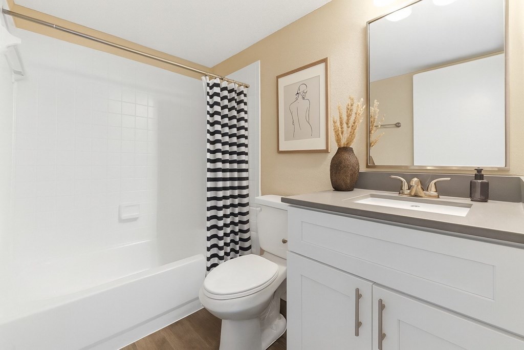 A bathroom with a white toilet and a checkered shower curtain.