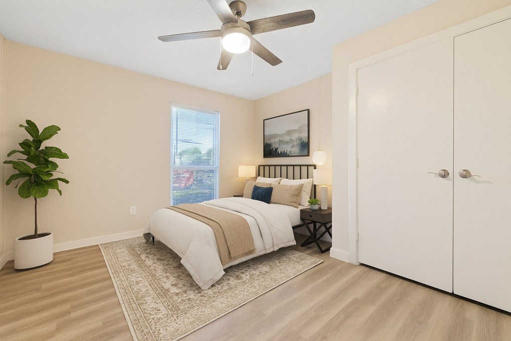 A bedroom with a bed, a ceiling fan, and a plant.