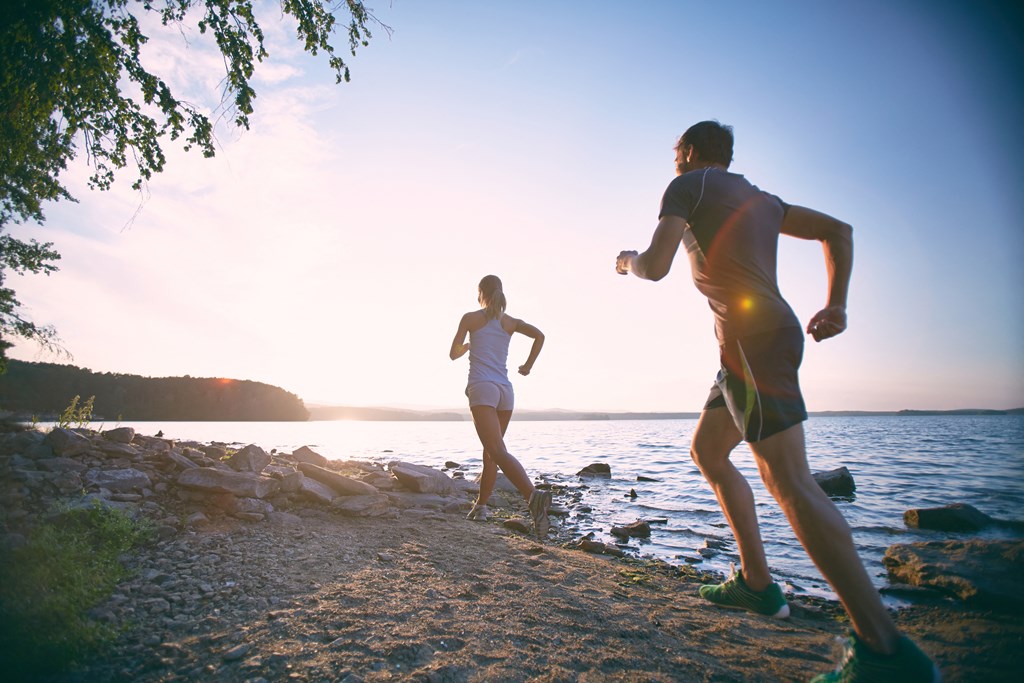a man and a woman running on the beach at sunset
