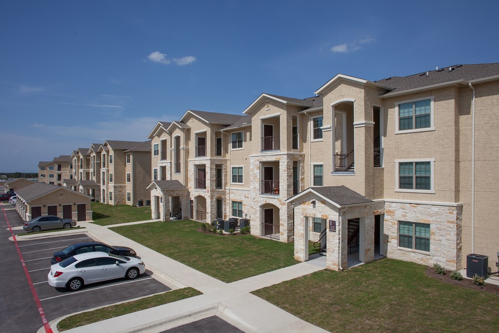 A car is parked in a parking lot in front of a building.