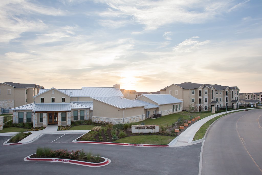A sunset view of a building with a parking lot in front.