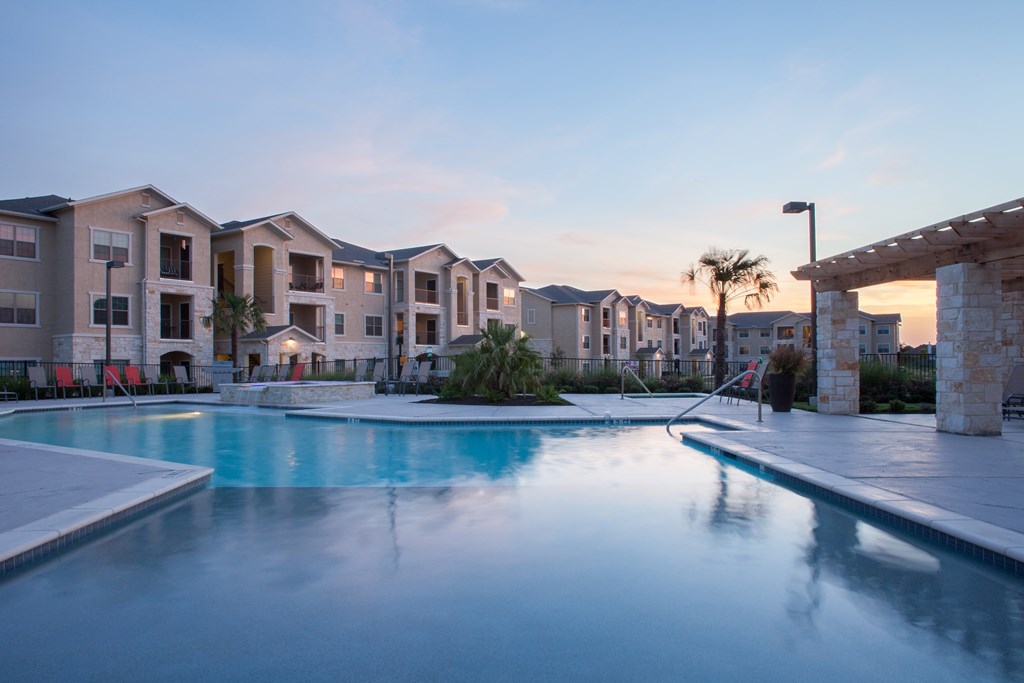 A swimming pool in front of apartment buildings at dusk.