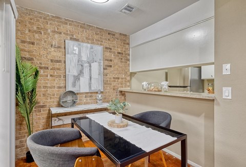 Small dining area outside a kitchen bartop with midcentury modern brick walls and brown concrete flooring