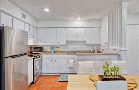 A kitchen with white cabinets and a wooden table.
