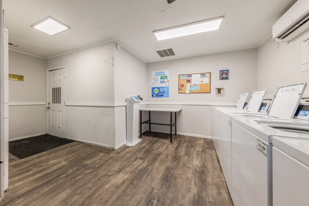 a laundry room with washers and dryers and a table with a chair