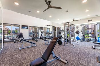 A spacious gym with a variety of equipment and a ceiling fan.