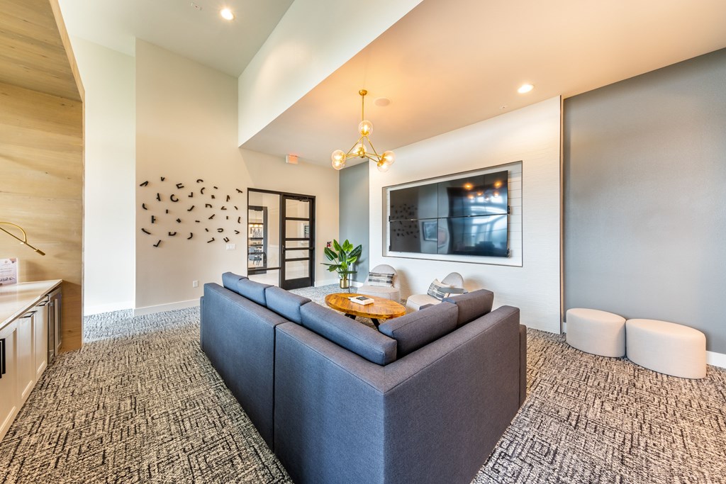 A grey couch with a yellow pillow is in the middle of a room with a carpet.