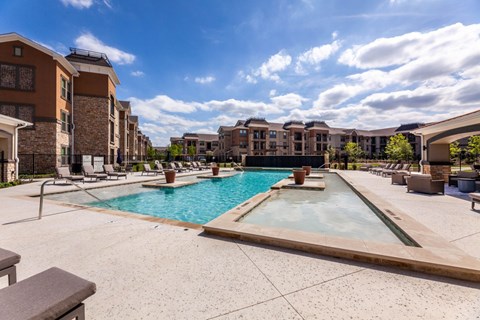A large outdoor swimming pool with a hot tub in the middle of a residential area.