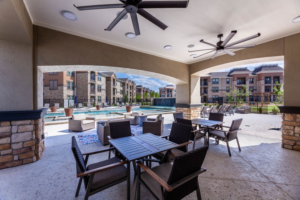 A patio with a table and chairs overlooking a pool.
