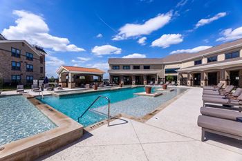 A large outdoor swimming pool with lounge chairs and a building in the background.