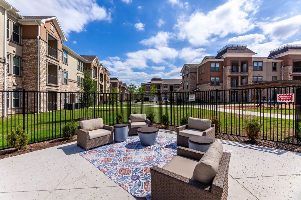 A patio with a rug and chairs in front of apartment buildings.