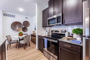 A modern kitchen with dark brown cabinets and stainless steel appliances.