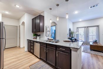 A kitchen with dark brown cabinets and a granite countertop.