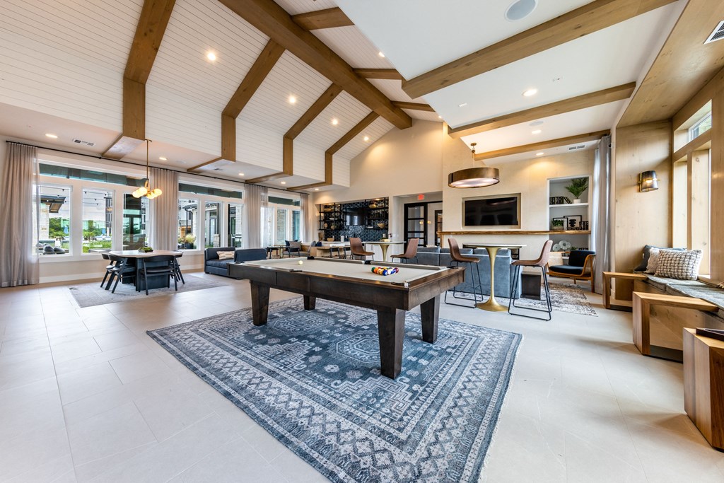 A spacious living room with a large rug and a long wooden table.