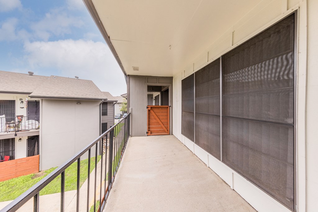a long balcony with a concrete walkway and a wooden door