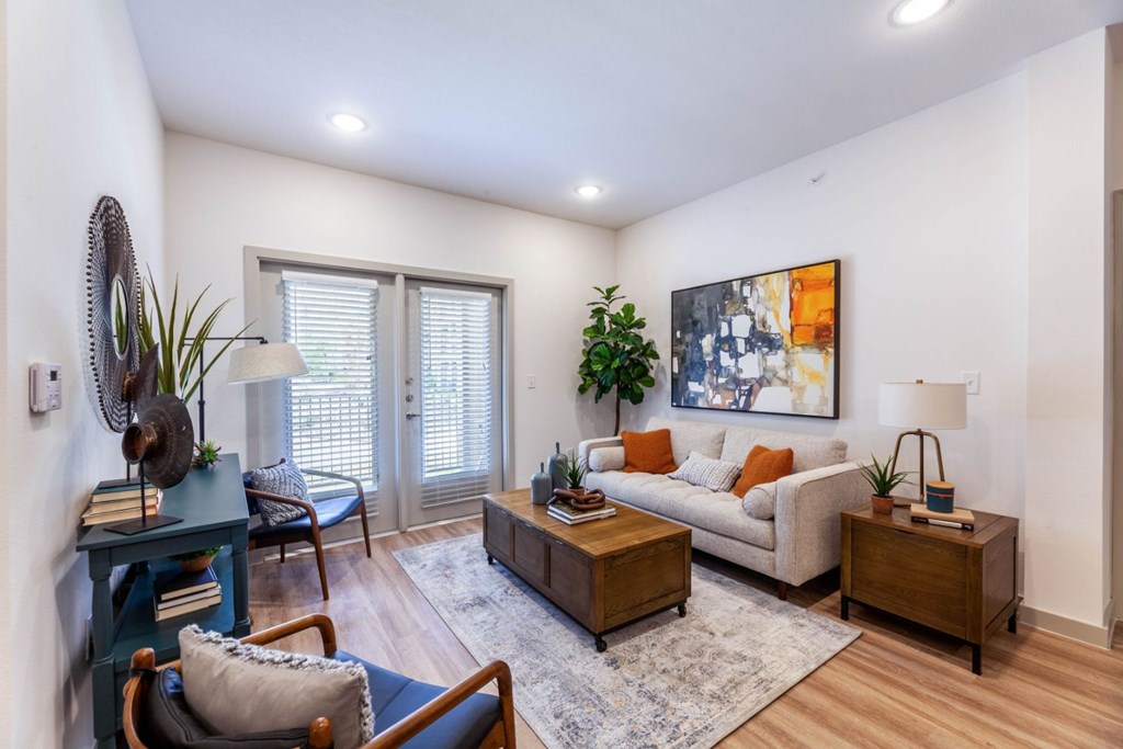 A living room with a couch, a chair, a table, and a painting on the wall.