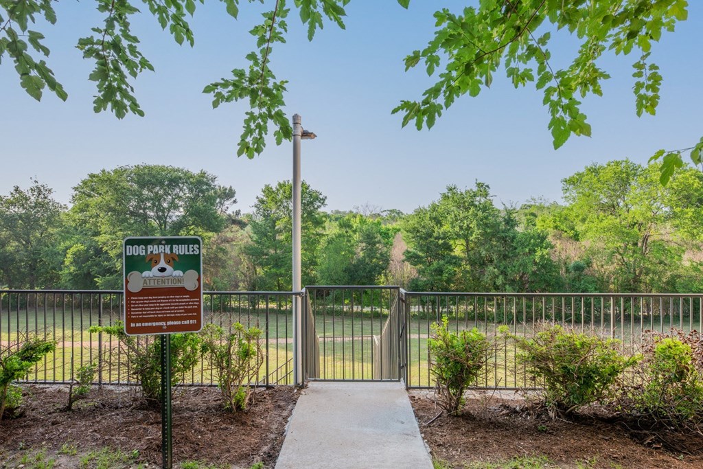 a sign for a park with a fence and trees